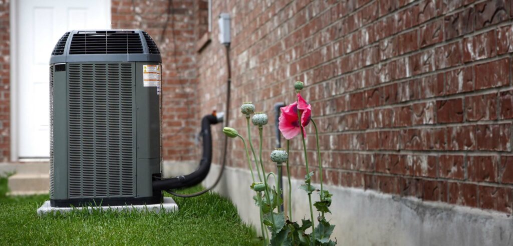 AC Unit outside a brick building with poppies in foreground.