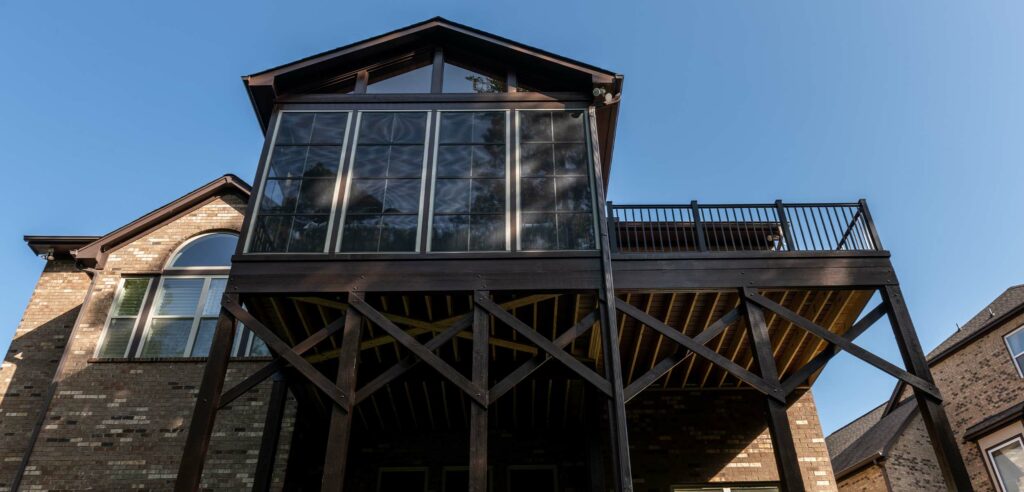 Upward view of large greenhouse with deck attached.