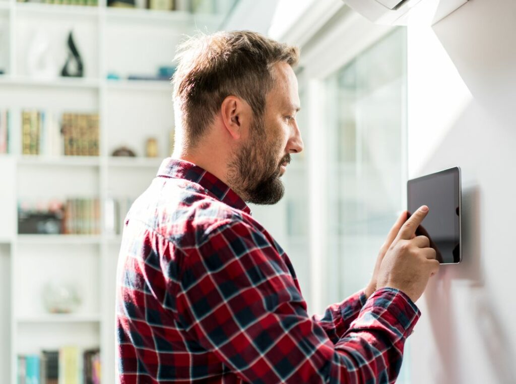 Man adjusts his smart home thermostat.