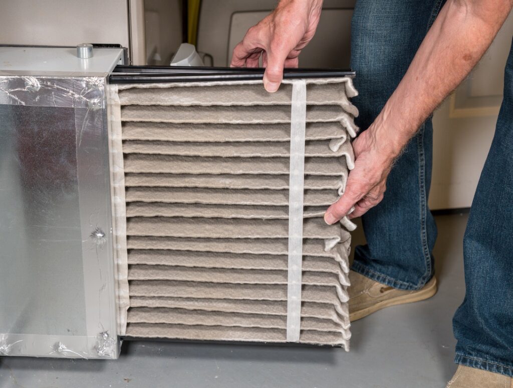 Homeowner replacing furnace filter before going on vacation