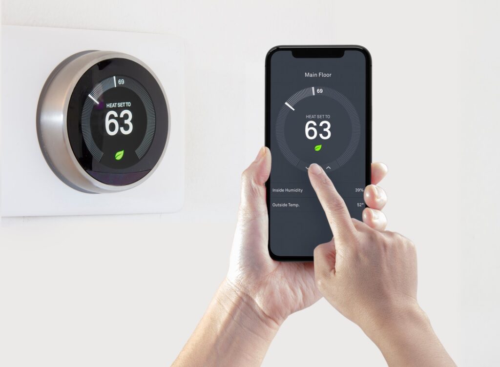 A person using a smart phone application saving energy with a wireless smart thermostat on a white background.