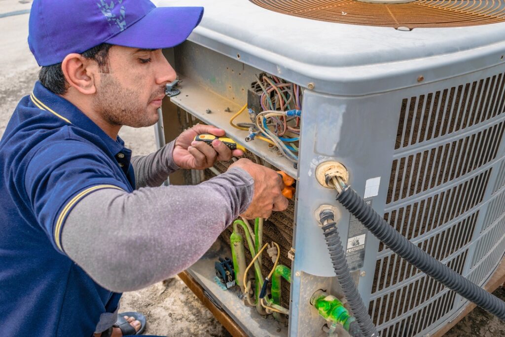 HVAC tech conducting AC repairs to minimize noise